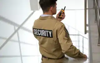 A business owner’s guide to hiring security guards in Fort Worth, featuring a guard on a stairwell using a walkie-talkie while ensuring safety, communication, and reliable protection for commercial properties.