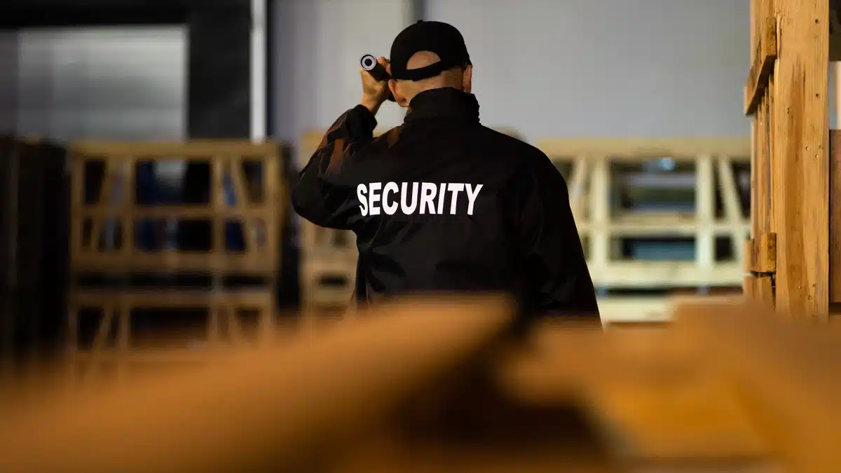 Fort Worth Construction Site Solutions for After-Hours Trespassing Fort Worth construction site solutions for preventing after-hours trespassing, illustrated by a security guard patrolling a warehouse with a flashlight to deter intruders and protect equipment.
